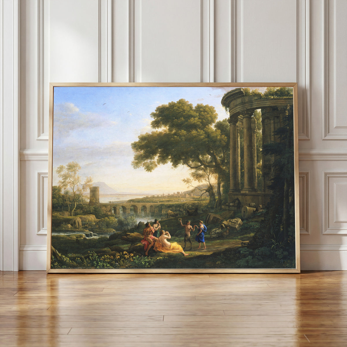 Framed art print of Landscape with Nymph and Satyr Dancing by Claude Lorrain, in a light wood frame leaning against a panelled white wall