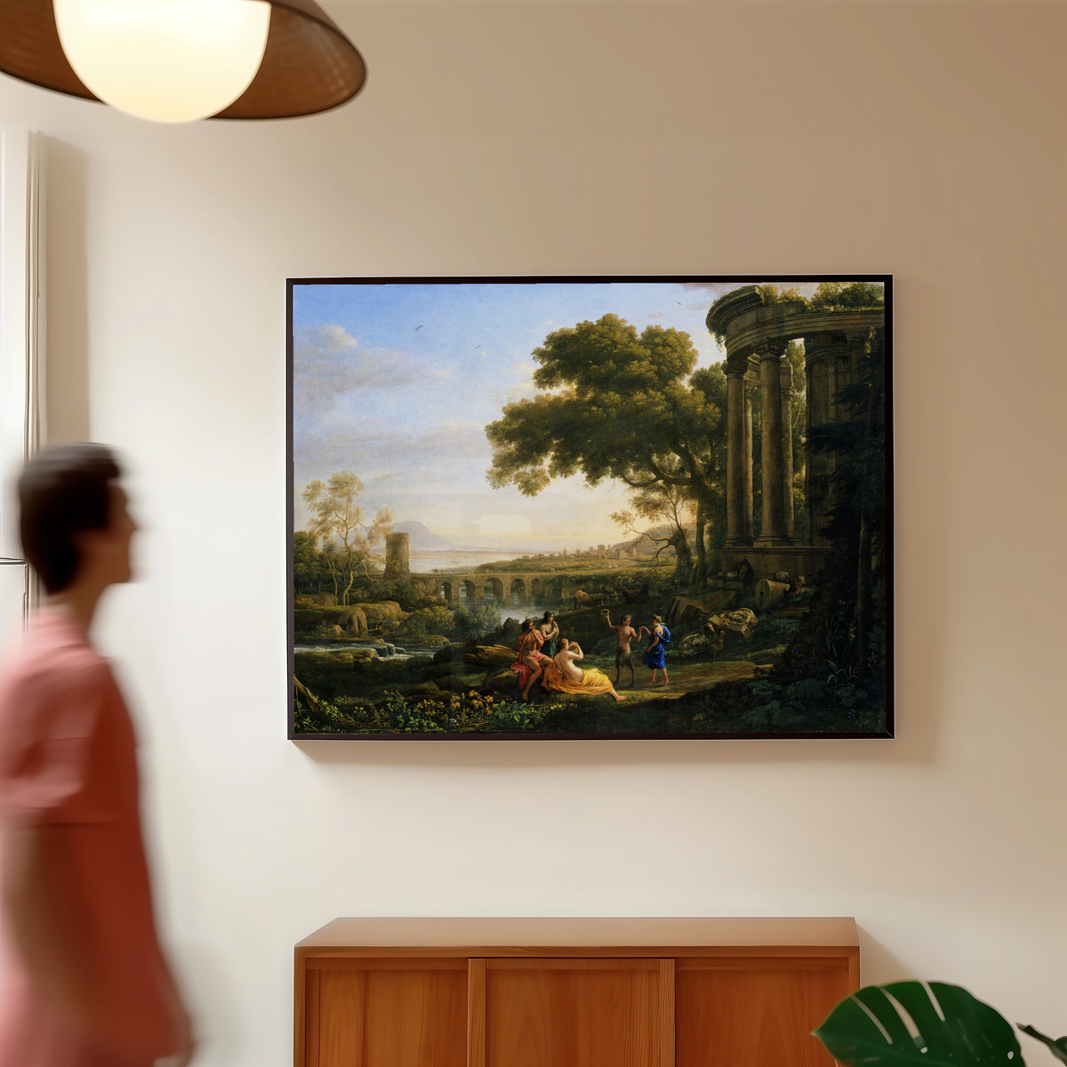 Framed art print of Landscape with Nymph and Satyr Dancing by Claude Lorrain, in a slim black frame on a warm wall in a sunlit room