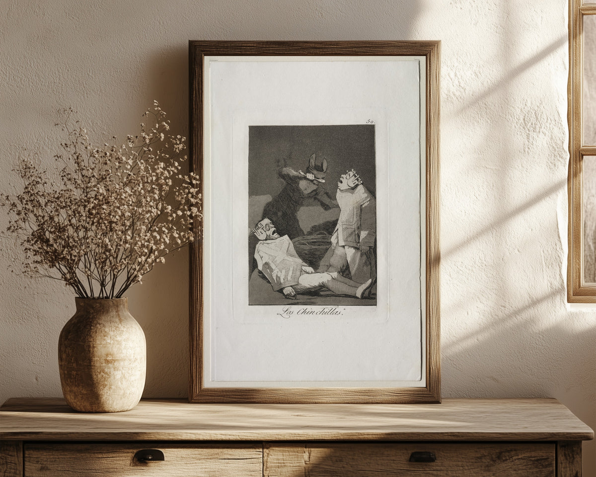 Framed art print of Las Chinchillas, Los Caprichos, Plate 50 by Francisco de Goya, in a dark wood frame leaning on a rustic console beside dried flowers