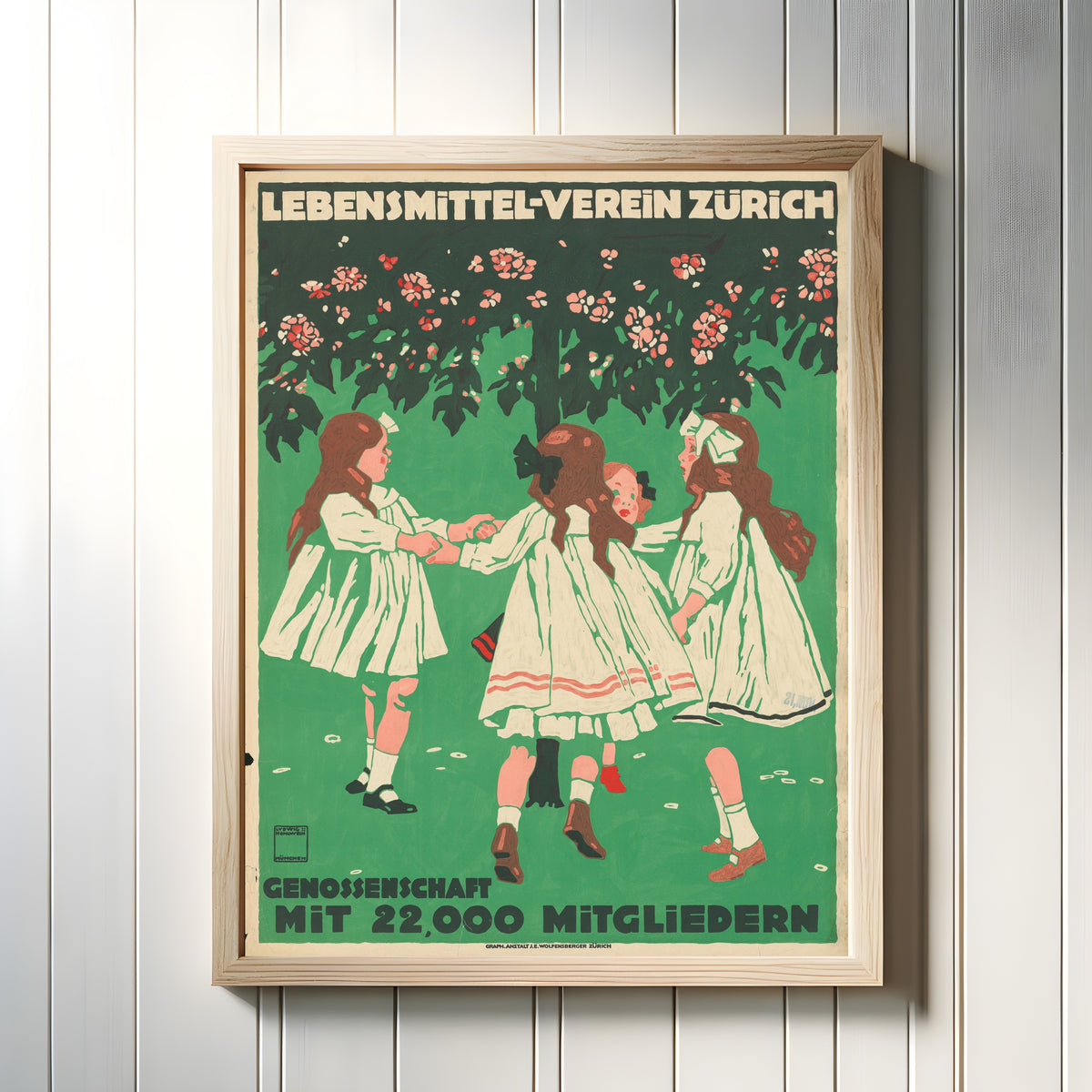 Framed art print of Lebensmittel-Verein Zürich by Ludwig Hohlwein, in a light wood frame on a white panelled wall