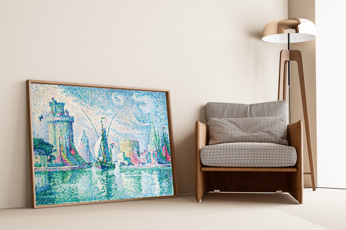 Framed art print of Les Tours Vertes, La Rochelle by Paul Signac, leaning against a wall beside an armchair and a floor lamp