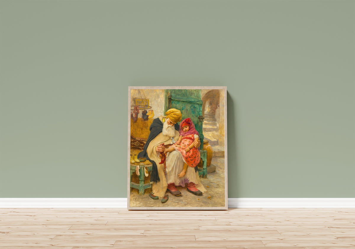 Framed art print of Les babouches by Frederick Arthur Bridgman, in a light wood frame leaning on a sage green wall above a wooden floor
