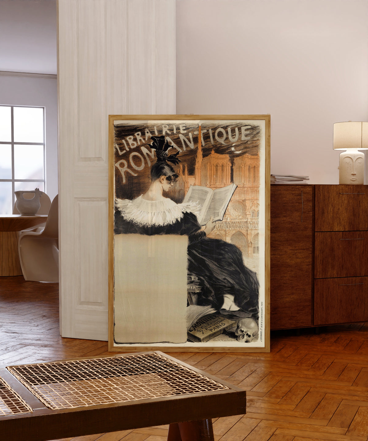 Framed art print of Librairie Romantique by Eugène Grasset, in a light wood frame leaning in a warm room with a parquet floor