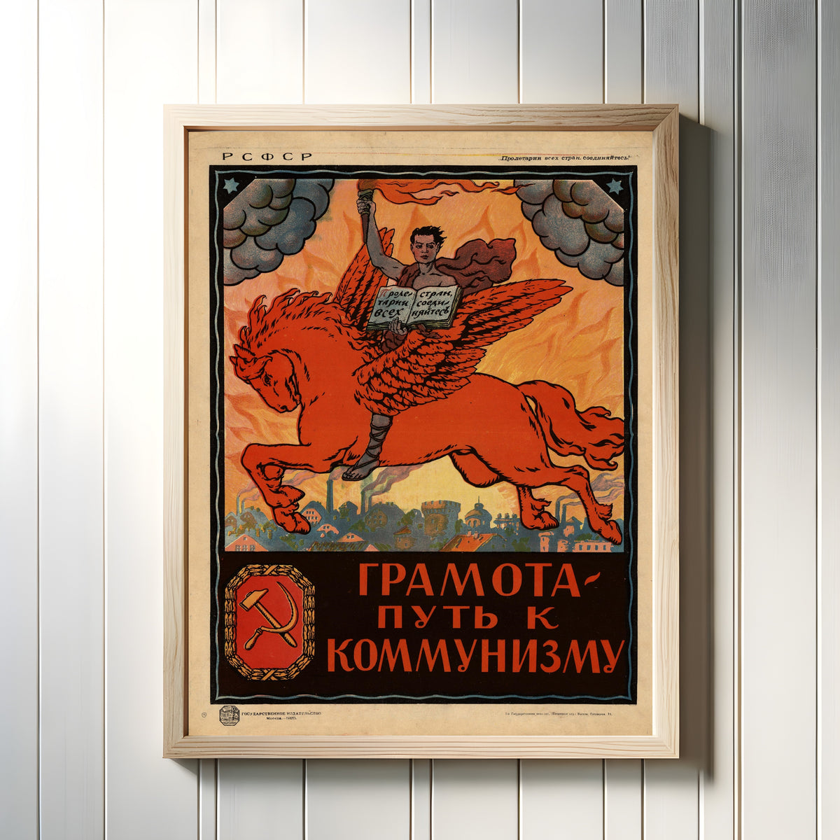 Framed art print of Literacy is the road to communism, in a light wood frame on a white panelled wall