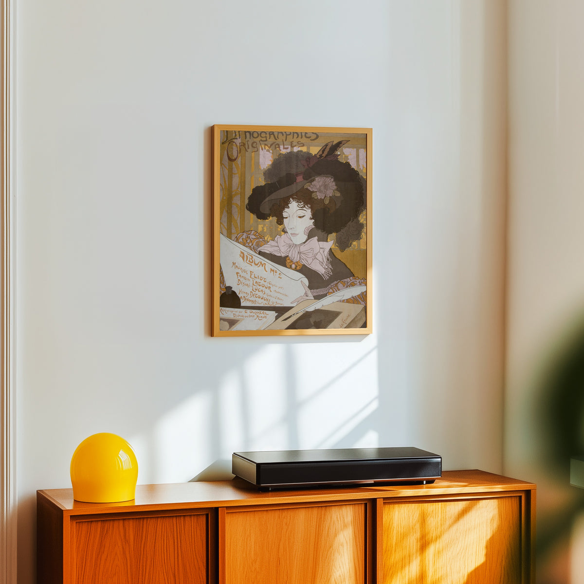 Framed art print of Lithographies originales, Album No 2 by Georges de Feure, in a light wood frame on a white wall above an orange sideboard