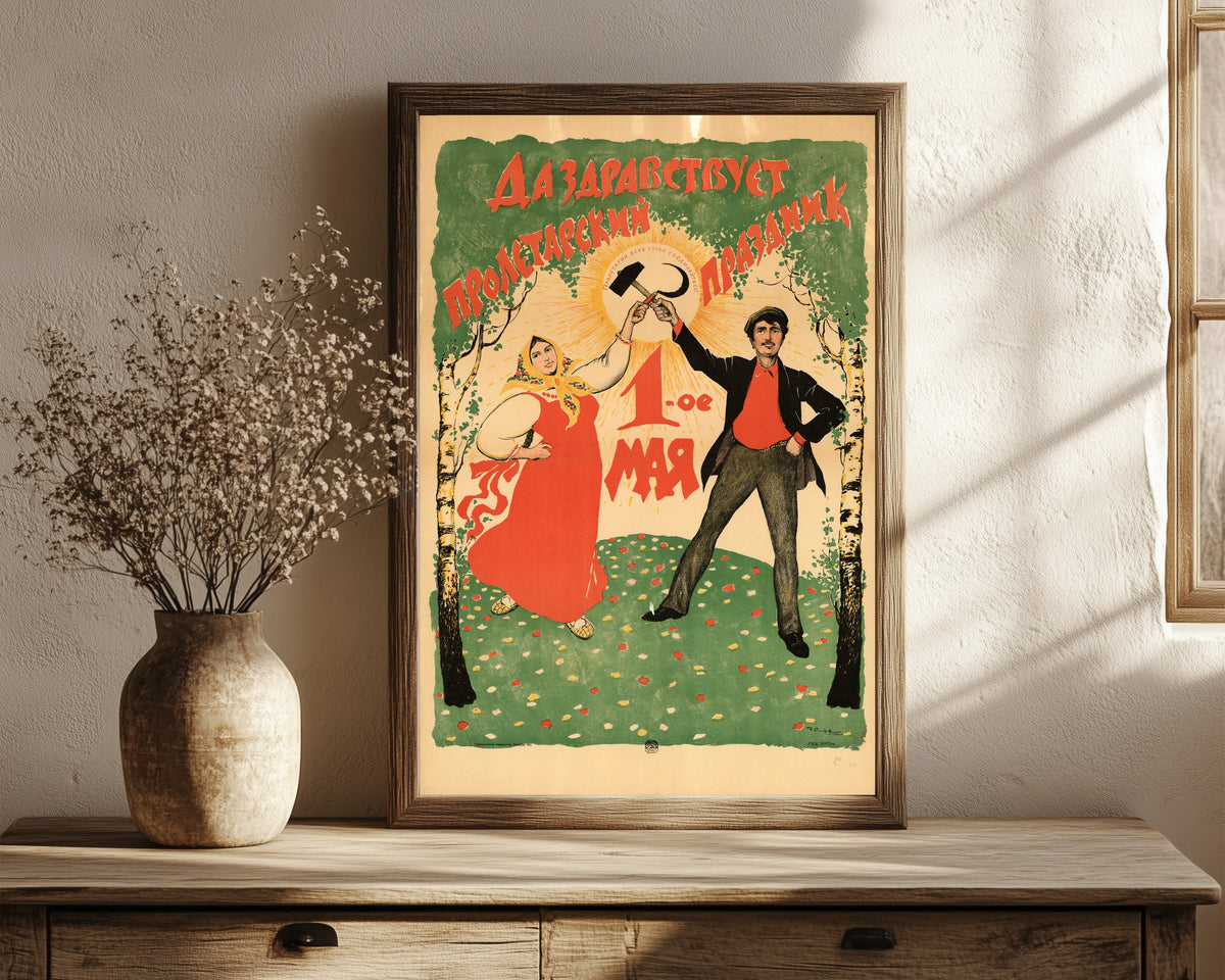 Framed art print of Long live the proletarian holiday, 1 May by Ivan Simakov, in a dark wood frame leaning on a rustic console beside dried flowers