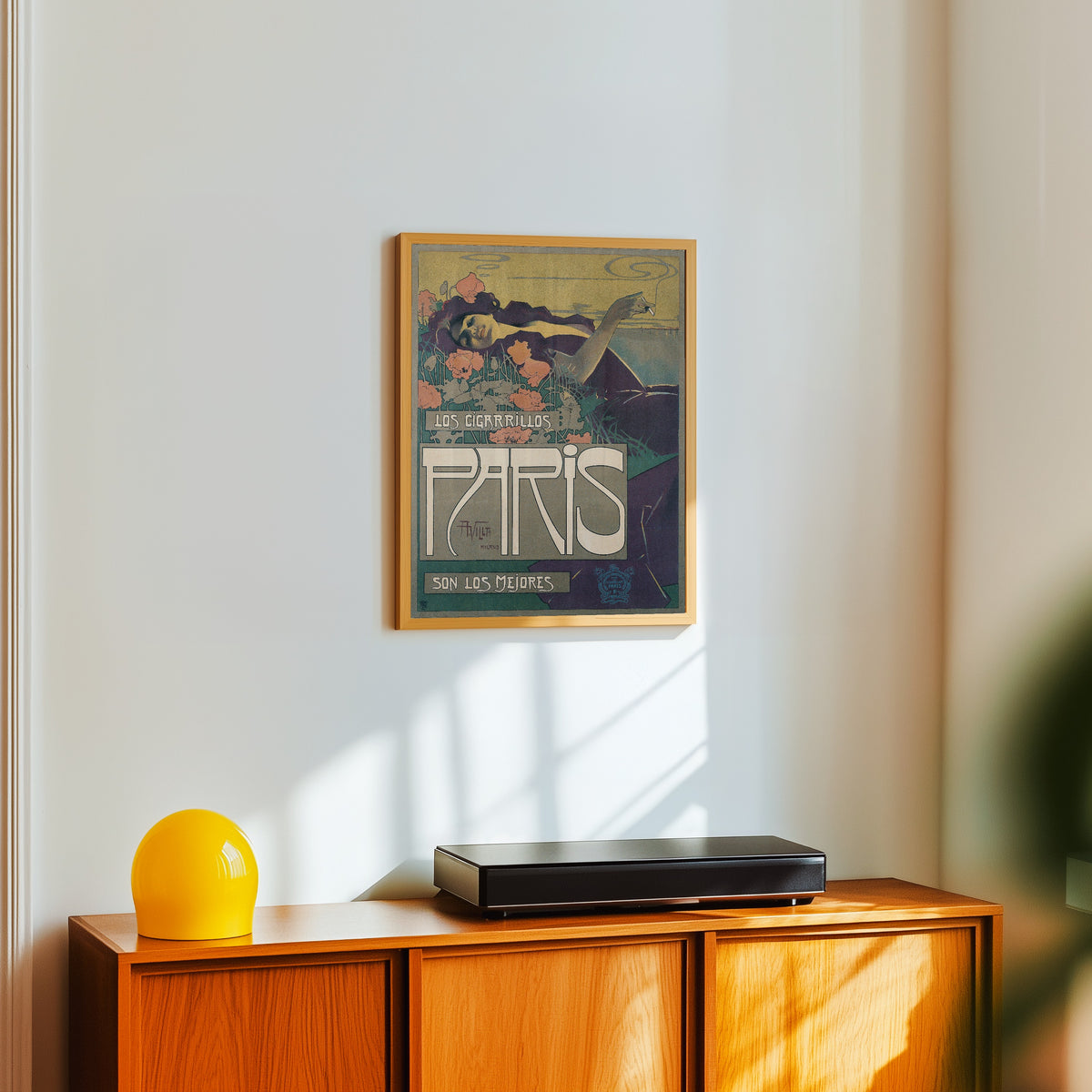 Framed art print of Los Cigarrillos Paris by Aleardo Villa, in a light wood frame on a white wall above an orange sideboard