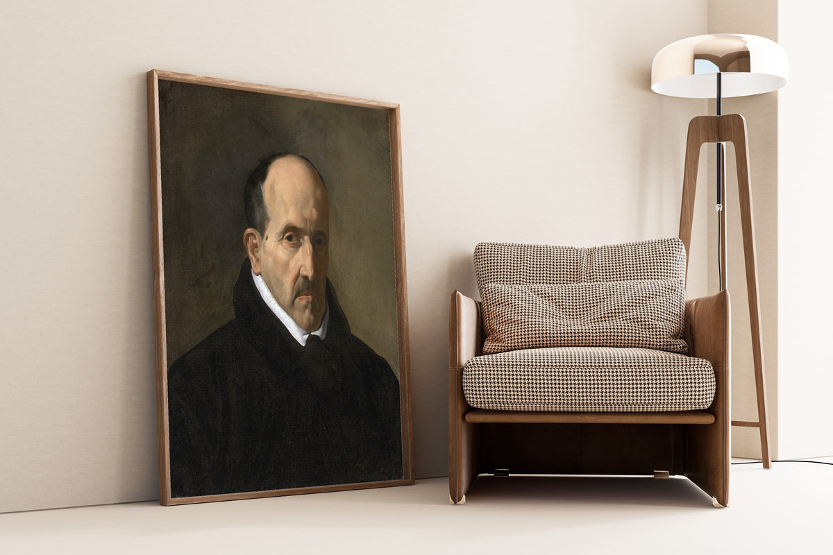 Framed art print of Luis de Góngora y Argote by Diego Velázquez, leaning against a wall beside an armchair and a floor lamp