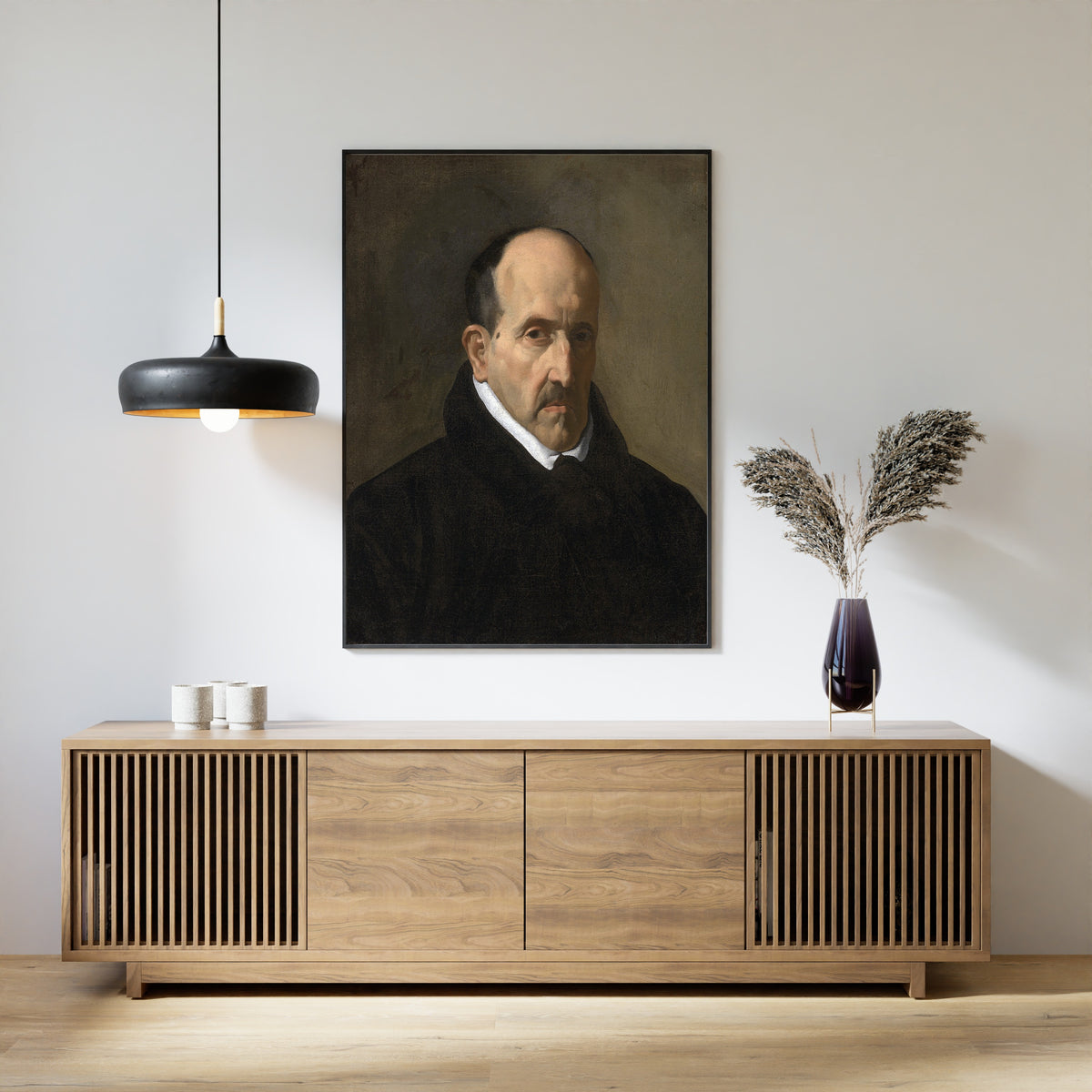 Framed art print of Luis de Góngora y Argote by Diego Velázquez, above a slatted wood sideboard