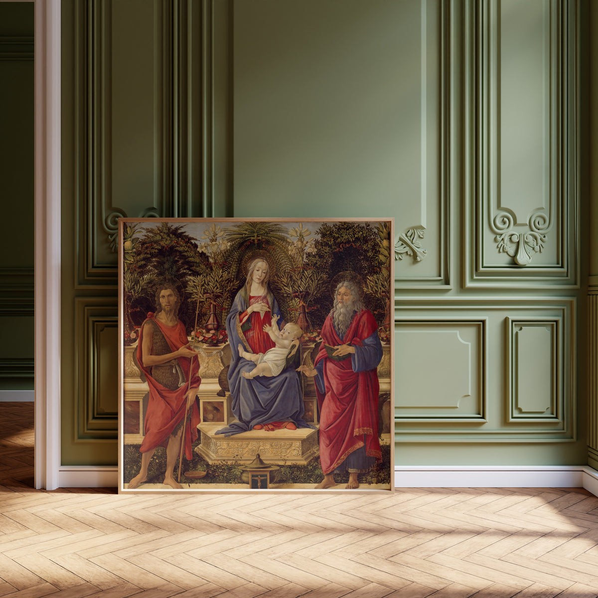 Framed art print of Madonna and Child with both Saints John by Sandro Botticelli, leaning against olive-green panelling on a herringbone floor