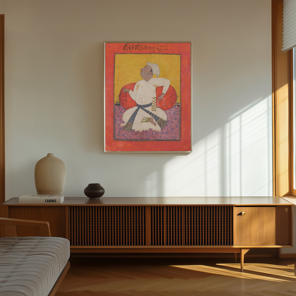 Framed art print of Maharaja Sital Dev in Devotion by Basohli school, in a thin light frame on a sunlit wall above a wooden sideboard
