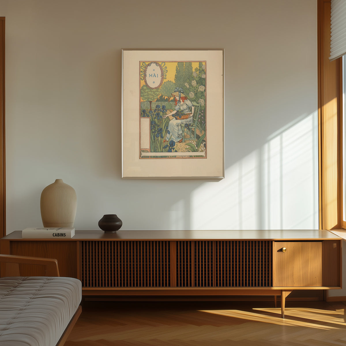 Framed art print of Mai by Eugène Grasset, in a thin light frame on a sunlit wall above a wooden sideboard