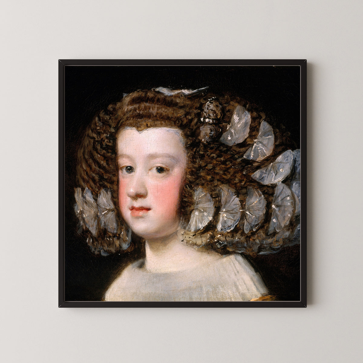 Framed art print of María Teresa, Infanta of Spain by Diego Velázquez, in a black frame on a pale wall