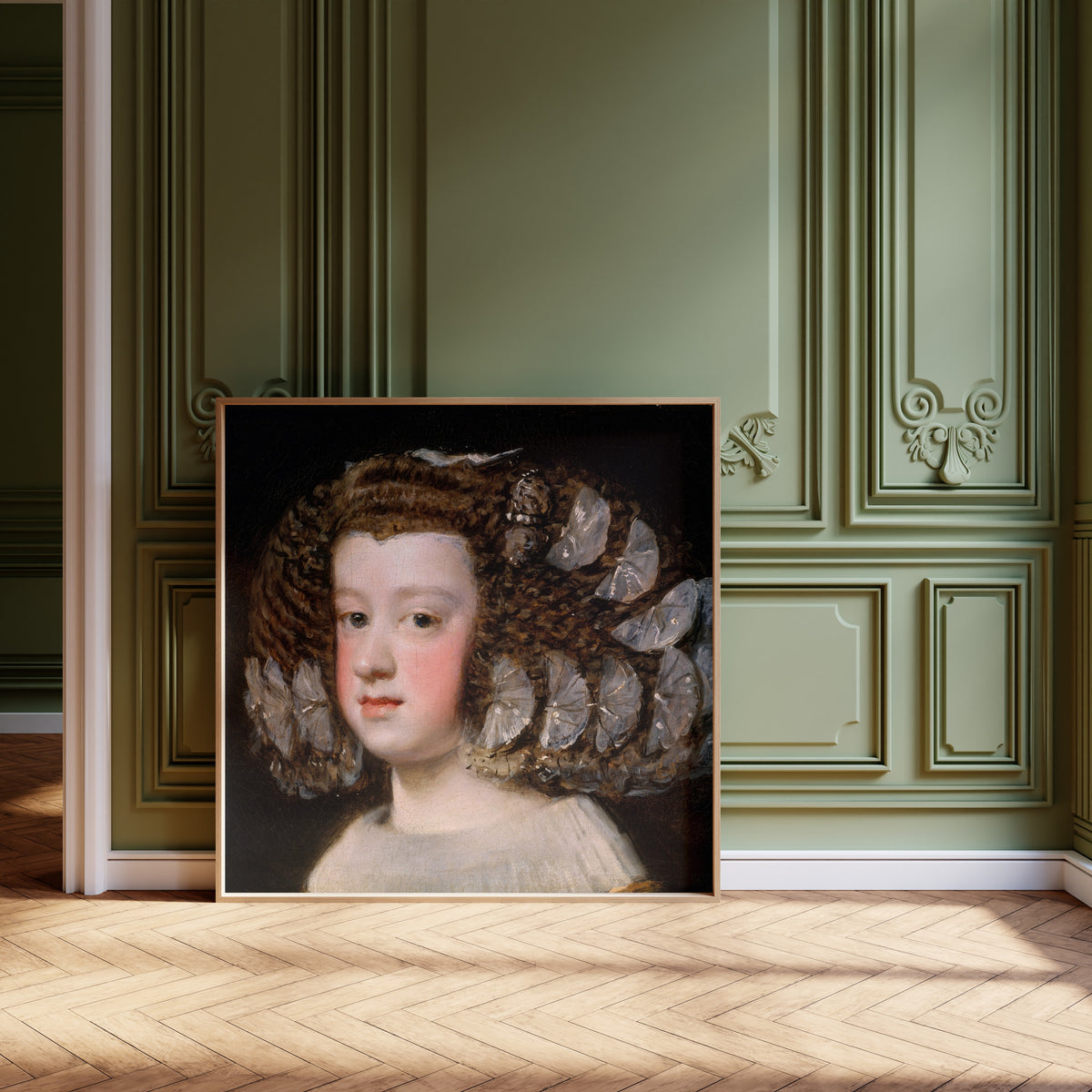 Framed art print of María Teresa, Infanta of Spain by Diego Velázquez, leaning against olive-green panelling on a herringbone floor