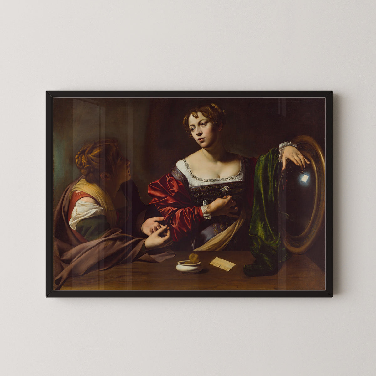 Framed art print of Martha and Mary Magdalene by Caravaggio, in a black frame on a pale wall