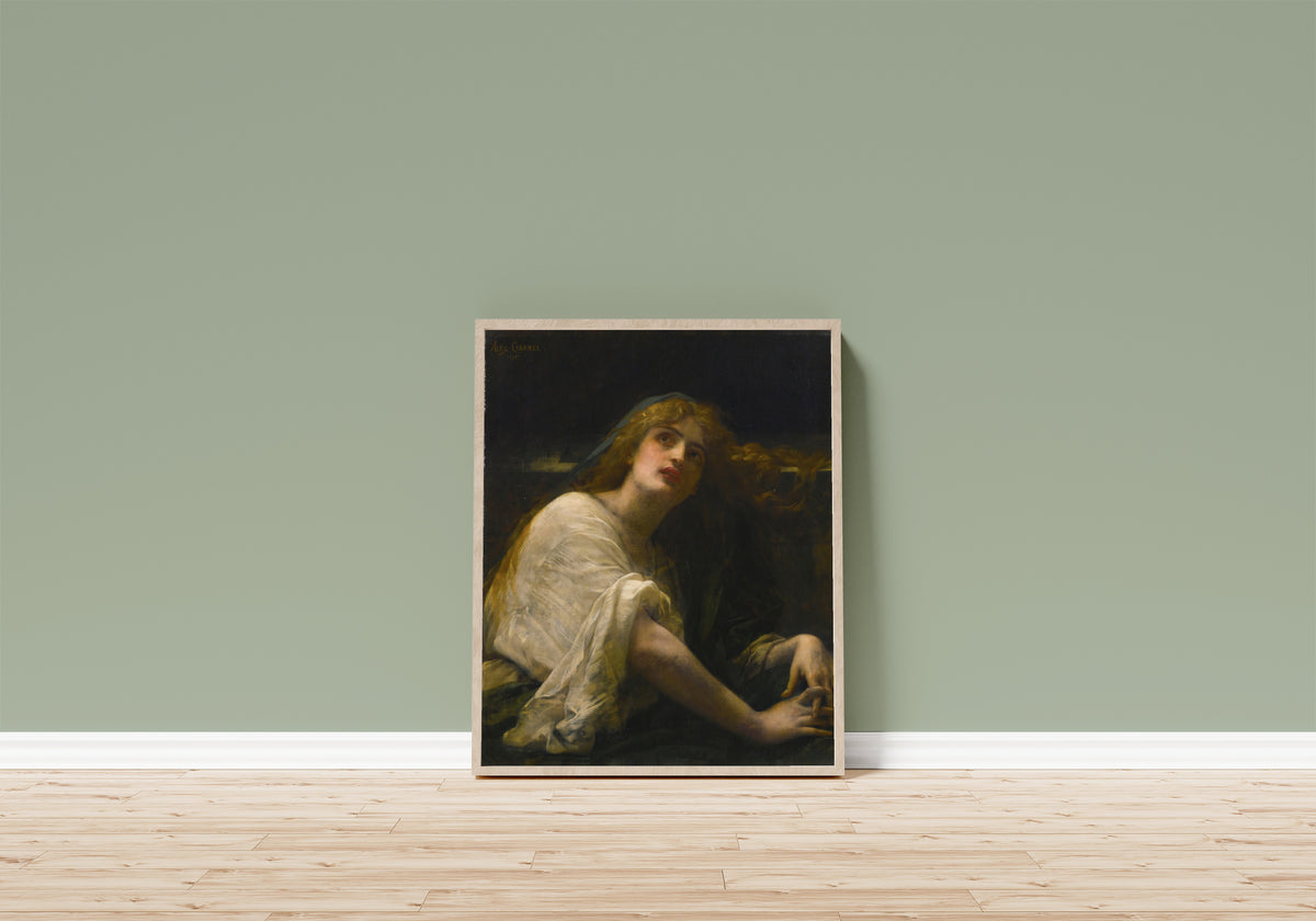 Framed art print of Mary Magdalene at the Tomb by Alexandre Cabanel, in a light wood frame leaning on a sage green wall above a wooden floor