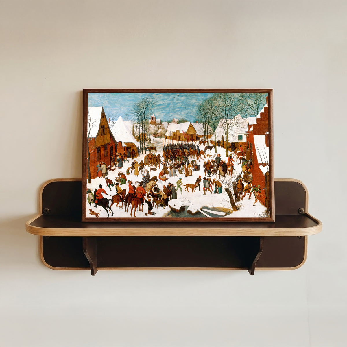Framed art print of Massacre of the Innocents by Pieter Bruegel the Elder, in a dark wood frame resting on a wall shelf