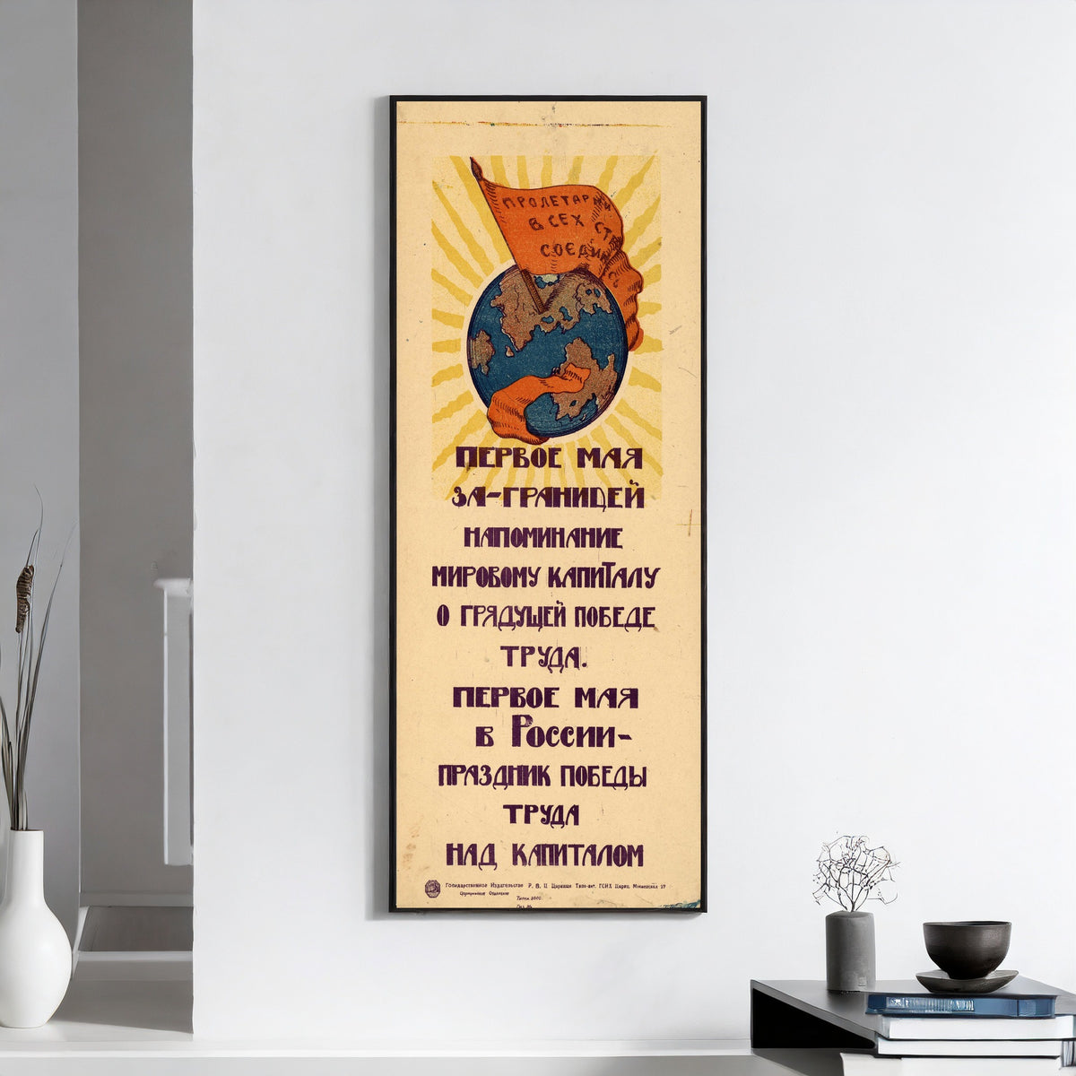 Framed art print of May Day abroad is a reminder to world capital of the coming victory of labour, on a white wall above books and a bowl