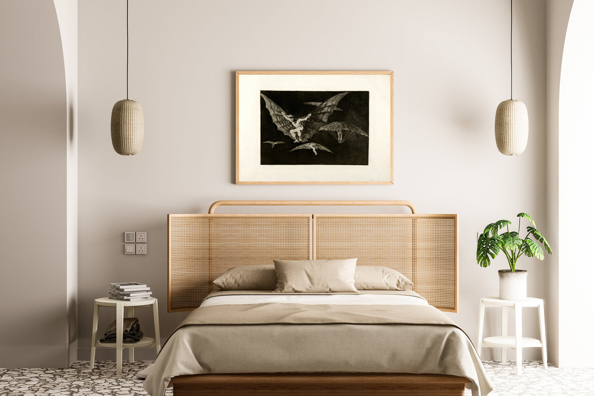 Framed art print of Modo de volar (A Way of Flying), from Los Disparates by Francisco de Goya, above a cane-headboard bed