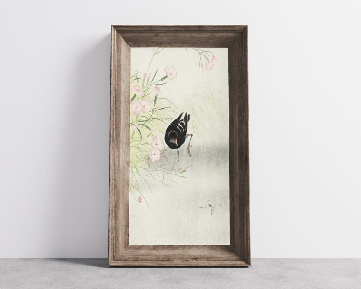 Framed art print of Moorhen at a Flowering Plant by Ohara Koson, in a wide wooden frame leaning against a concrete wall