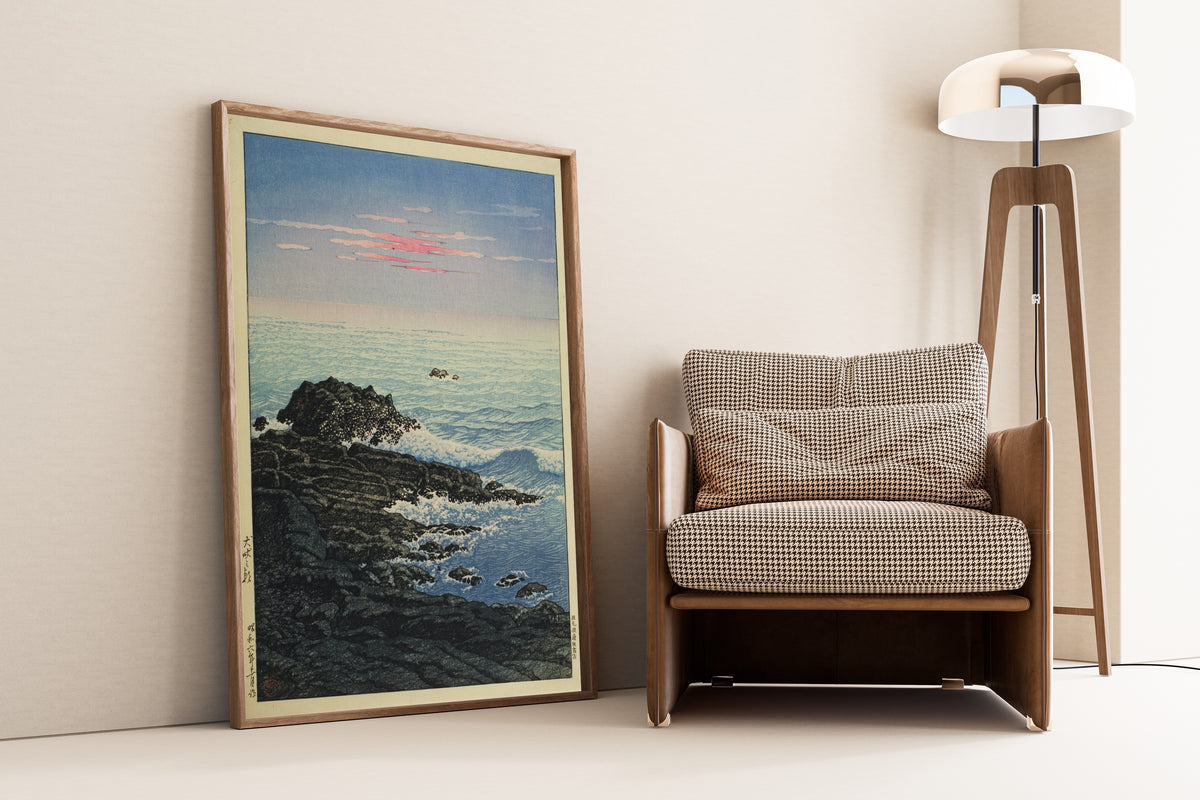 Framed art print of Morning at Cape Inubo by Kawase Hasui, leaning against a wall beside an armchair and a floor lamp