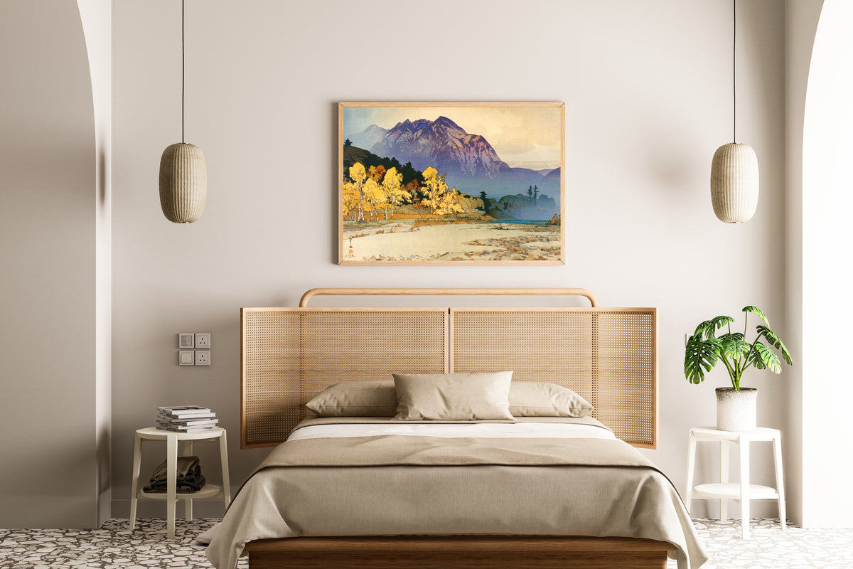Framed art print of Mount Hodaka after Rain by Hiroshi Yoshida, above a cane-headboard bed