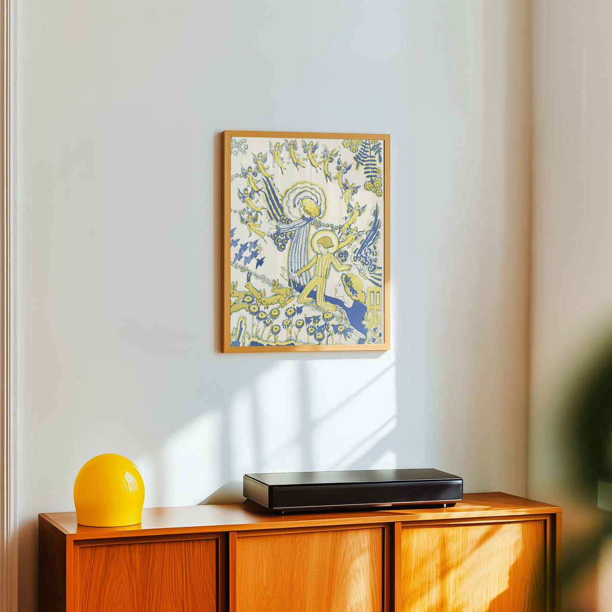 Framed art print of Mummy's Bedtime Story Book: Plate 12 by Jessie M. King, in a light wood frame on a white wall above an orange sideboard