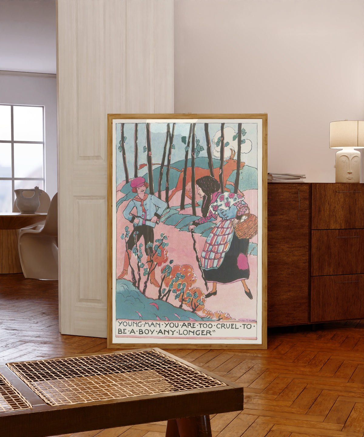 Framed art print of Mummy's Bedtime Story Book: Young Man You Are Too… by Jessie M. King, in a light wood frame leaning in a warm room with a parquet floor