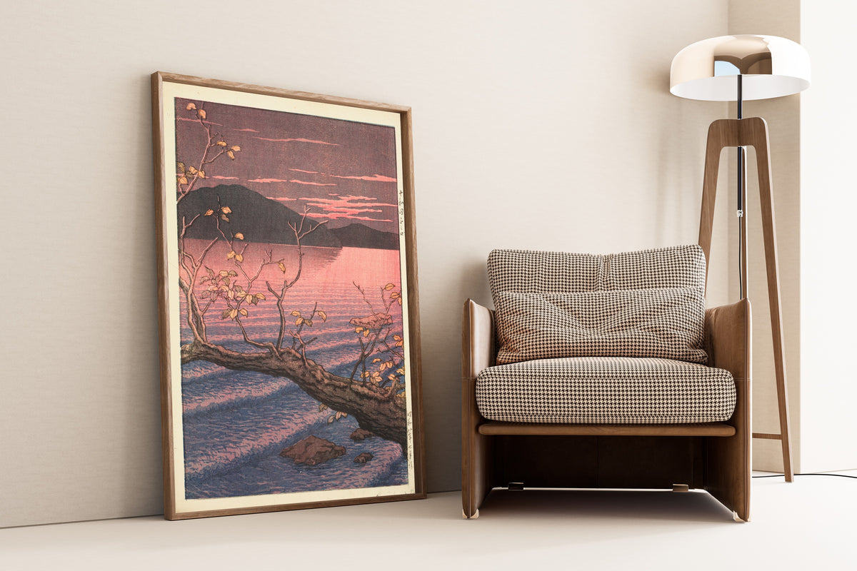 Framed art print of Nenokuchi, Lake Towada by Kawase Hasui, leaning against a wall beside an armchair and a floor lamp
