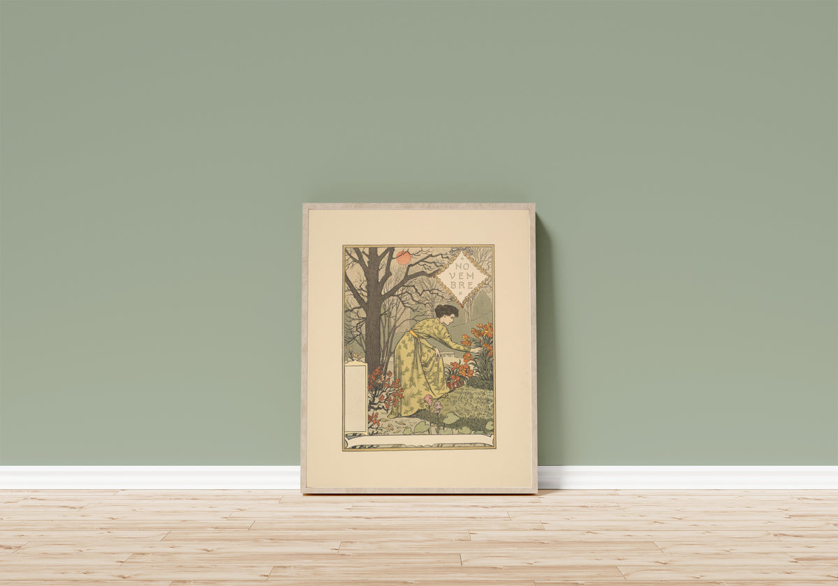 Framed art print of Novembre by Eugène Grasset, in a light wood frame leaning on a sage green wall above a wooden floor