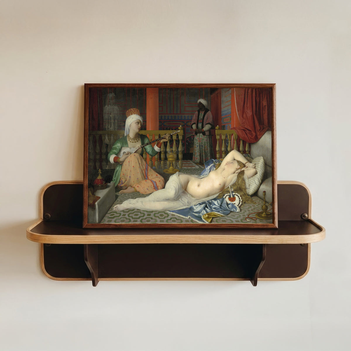 Framed art print of Odalisque with Slave by Jean-Auguste-Dominique Ingres, in a dark wood frame resting on a wall shelf