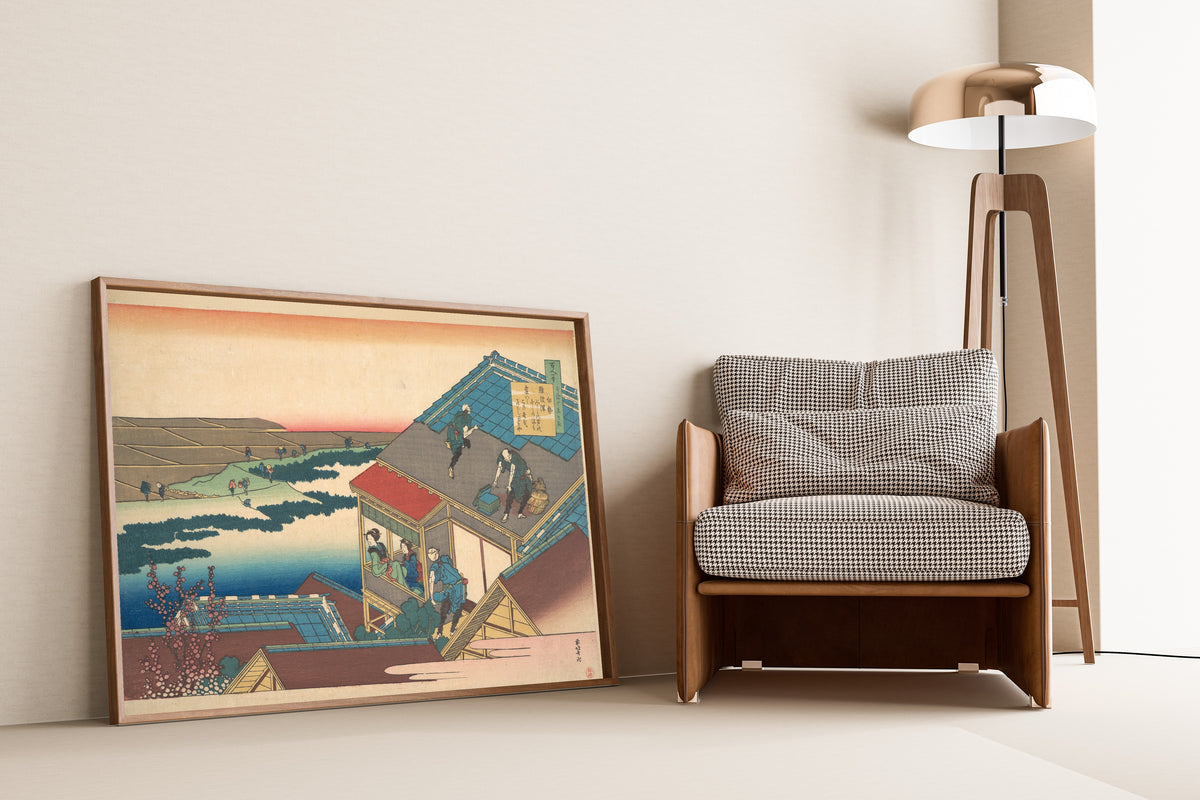 Framed art print of One Hundred Poems Explained by the Nurse: Poem by Ise by Katsushika Hokusai, leaning against a wall beside an armchair and a floor lamp