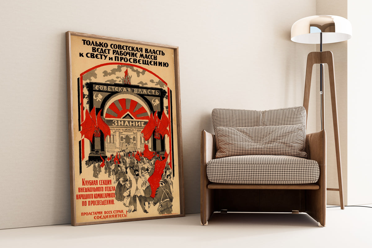 Framed art print of Only Soviet Power Leads the Working Masses to Light and Enlightenment, leaning against a wall beside an armchair and a floor lamp