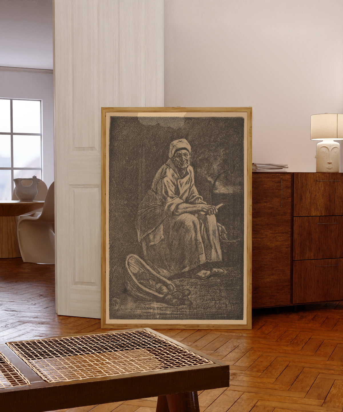 Framed art print of Oude-Kate by Félicien Rops, in a light wood frame leaning in a warm room with a parquet floor