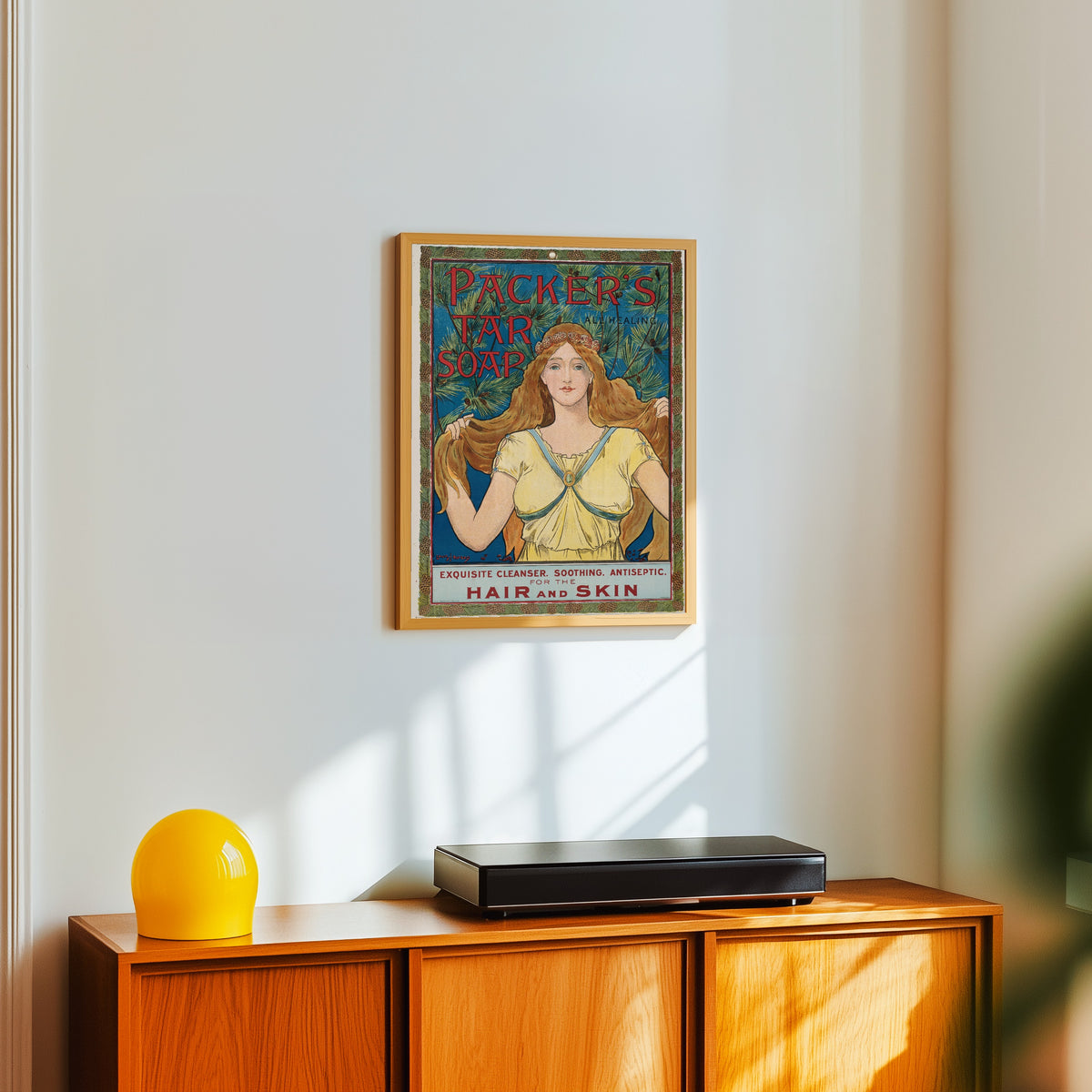 Framed art print of Packer's Tar Soap by Louis Rhead, in a light wood frame on a white wall above an orange sideboard