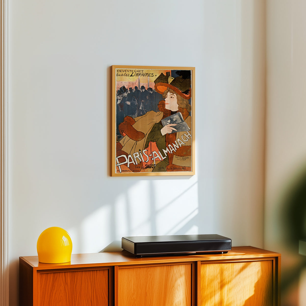 Framed art print of Paris-Almanach by Georges de Feure, in a light wood frame on a white wall above an orange sideboard