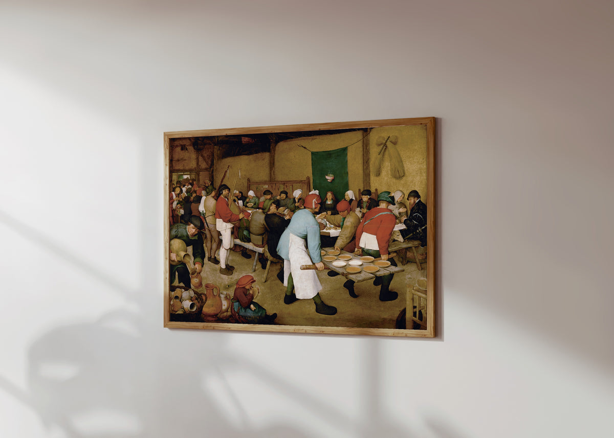 Framed art print of Peasant Wedding by Pieter Bruegel the Elder, in a light wood frame on a sunlit white wall, seen at a slight angle