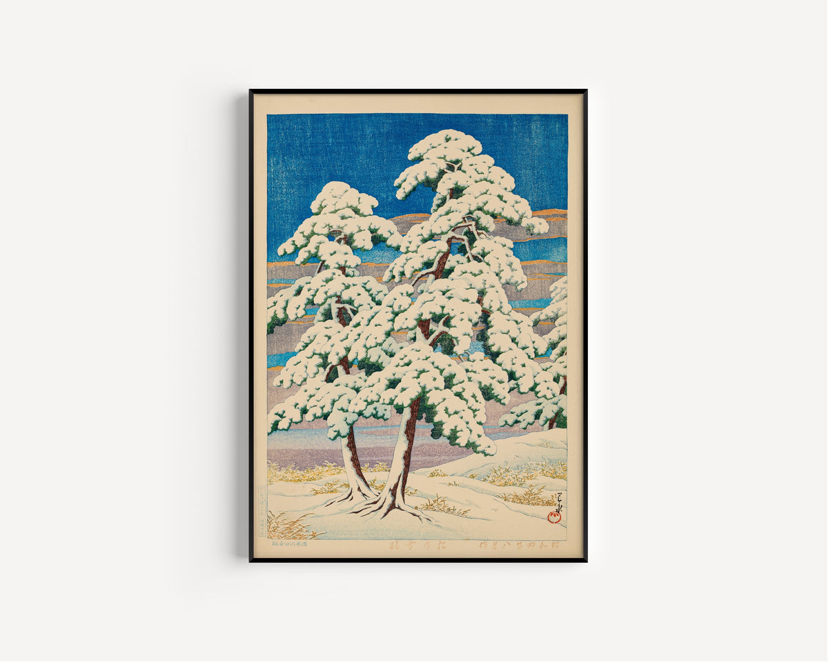 Framed art print of Pines in Clear Weather After Snow by Kawase Hasui, in a slim black frame on a plain white wall