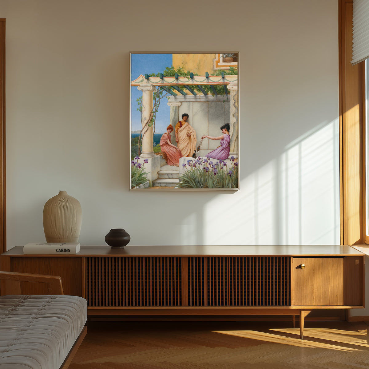 Framed art print of Playtime by John William Godward, in a thin light frame on a sunlit wall above a wooden sideboard