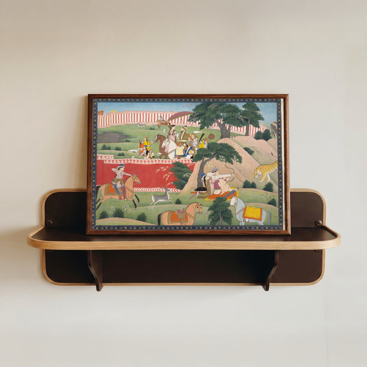 Framed art print of Pleasures of the Hunt by Kangra school, in a dark wood frame resting on a wall shelf