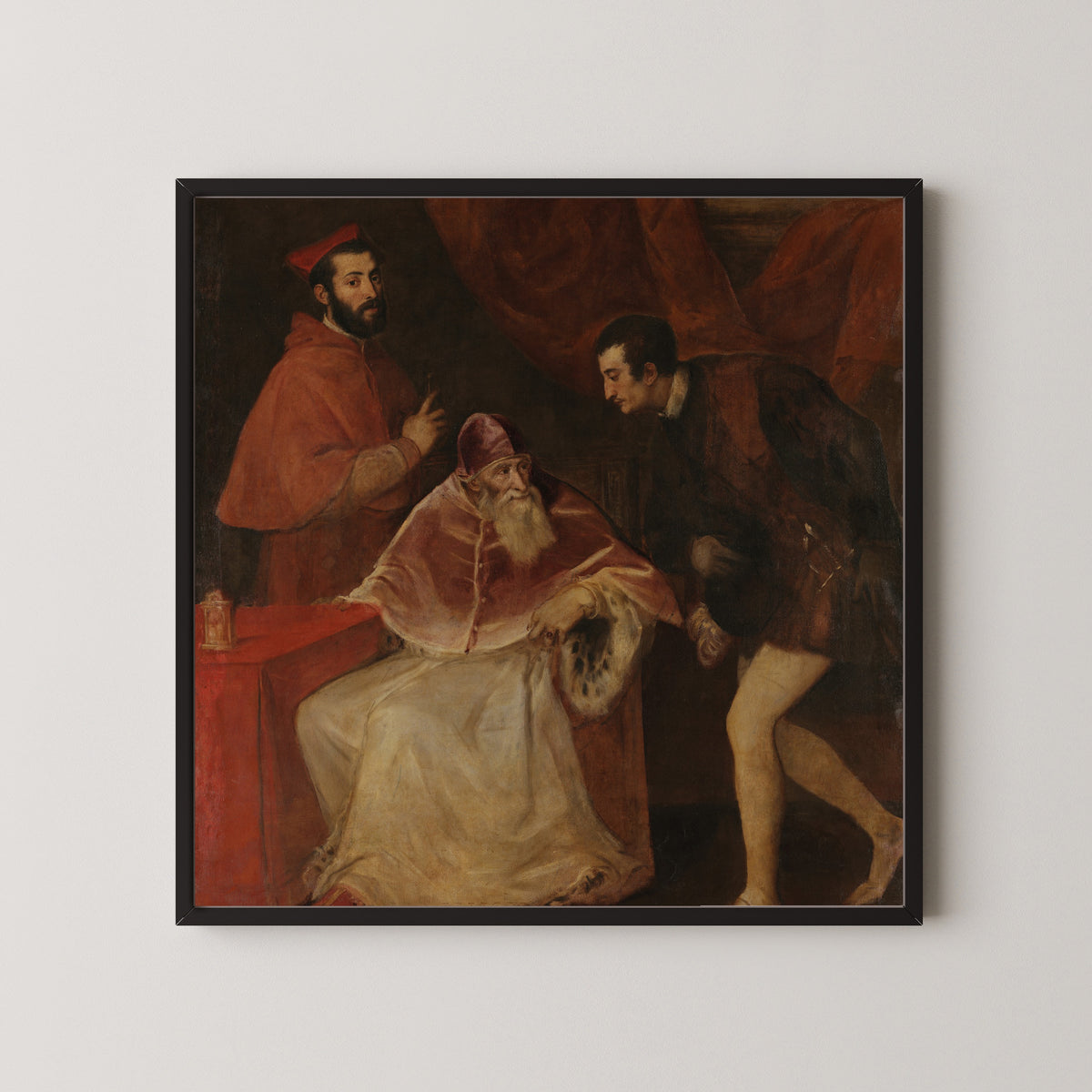 Framed art print of Pope Paul III and His Grandsons by Titian, in a black frame on a pale wall
