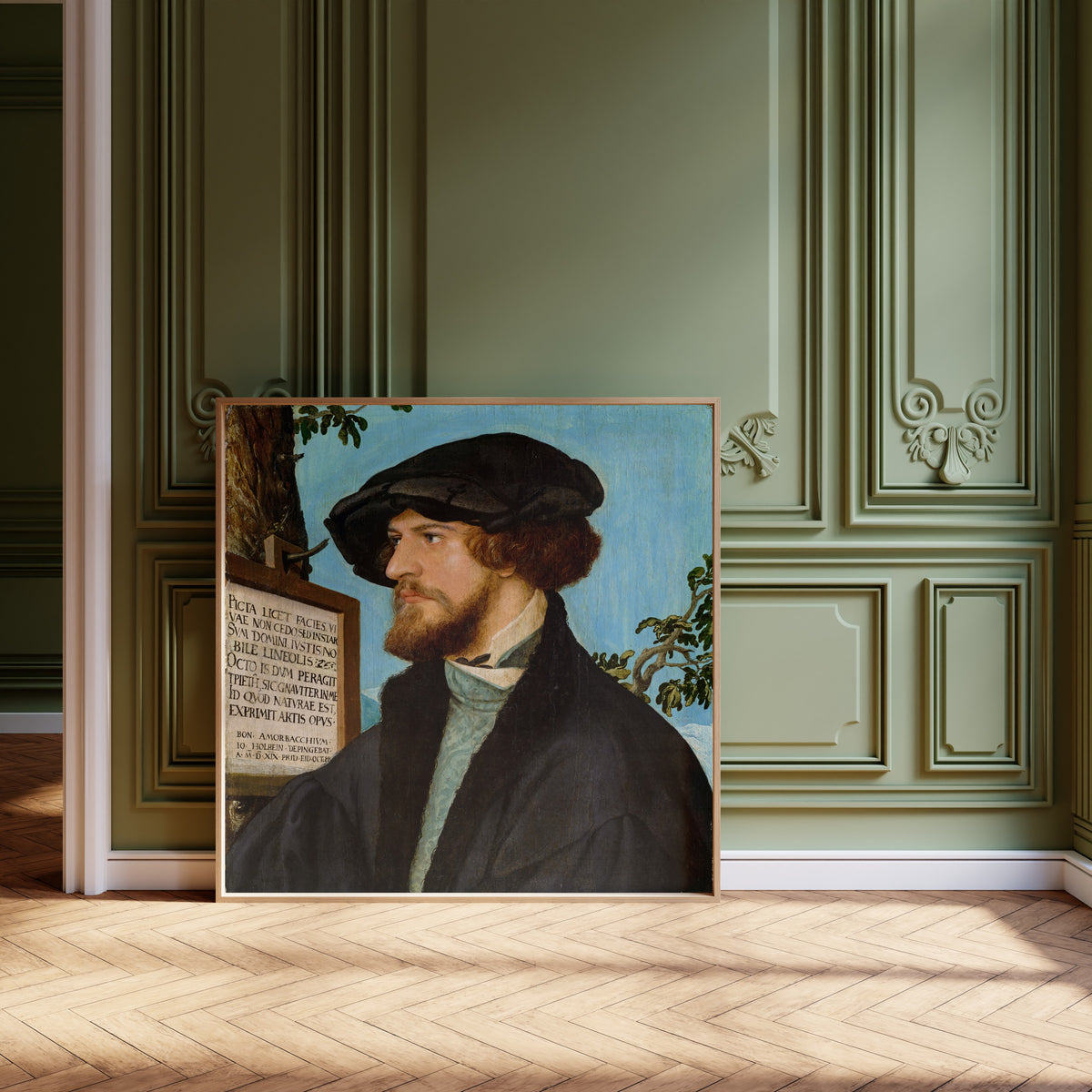 Framed art print of Portrait of Bonifacius Amerbach by Hans Holbein the Younger, leaning against olive-green panelling on a herringbone floor