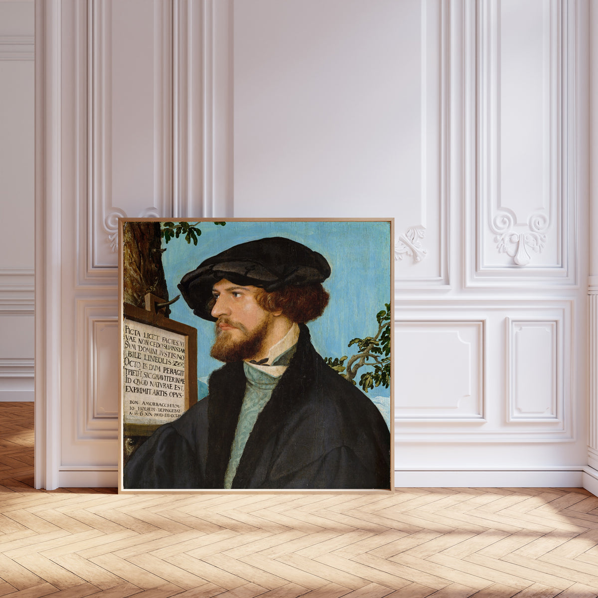 Framed art print of Portrait of Bonifacius Amerbach by Hans Holbein the Younger, leaning against pale pink panelling on a herringbone floor