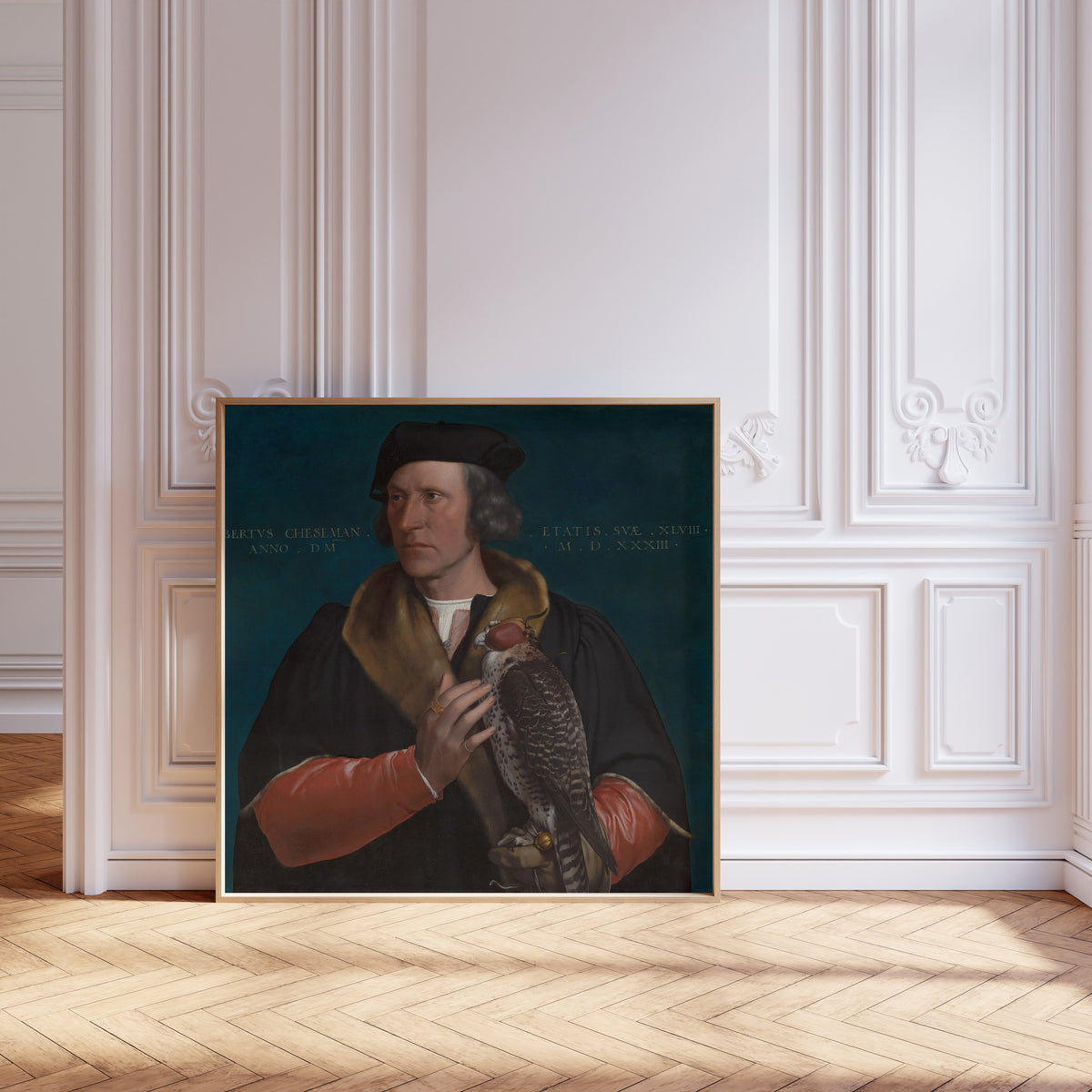 Framed art print of Portrait of Robert Cheseman by Hans Holbein the Younger, leaning against pale pink panelling on a herringbone floor