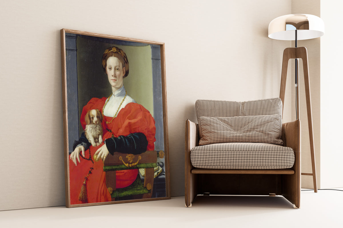 Framed art print of Portrait of a Lady in Red (Francesca Salviati) by Bronzino, leaning against a wall beside an armchair and a floor lamp