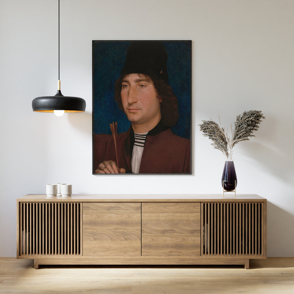 Framed art print of Portrait of a Man with an Arrow by Hans Memling, above a slatted wood sideboard