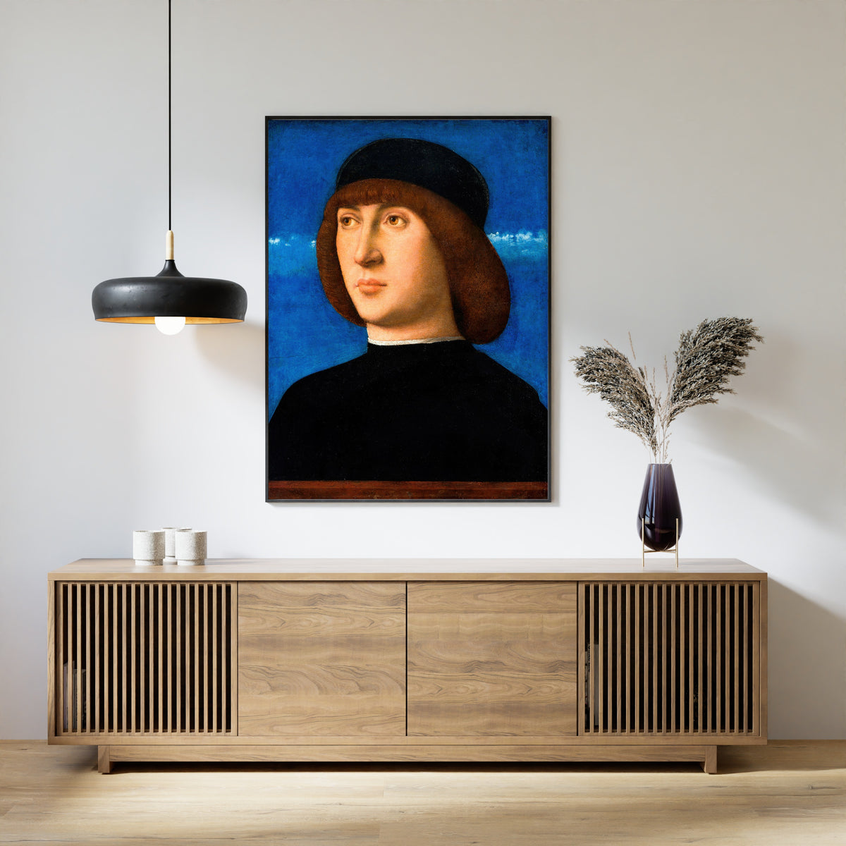 Framed art print of Portrait of a Young Man by Giovanni Bellini, above a slatted wood sideboard