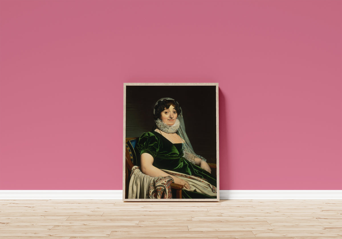 Framed art print of Portrait of the Countess of Tournon by Jean-Auguste-Dominique Ingres, in a light wood frame leaning on a pink wall above a wooden floor