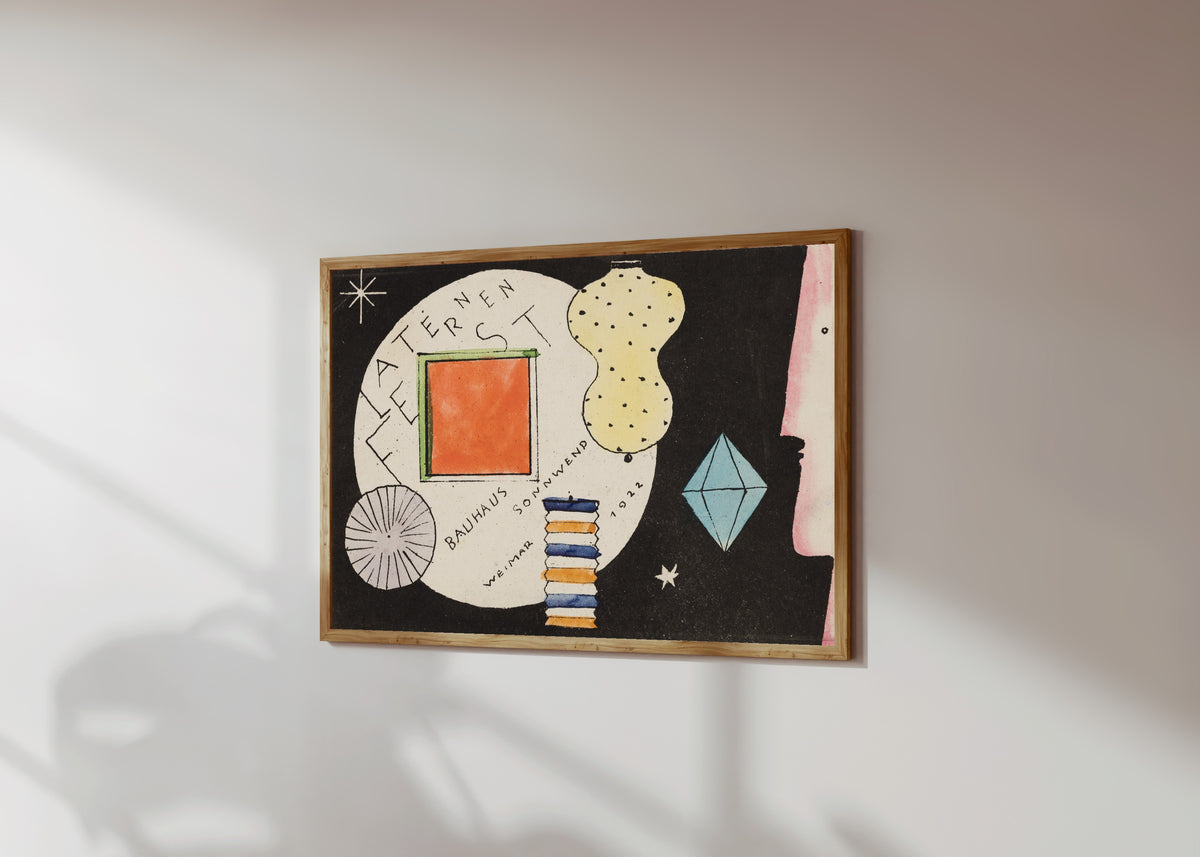 Framed art print of Postcard invitation to a lantern festival by Oskar Schlemmer, in a light wood frame on a sunlit white wall, seen at a slight angle