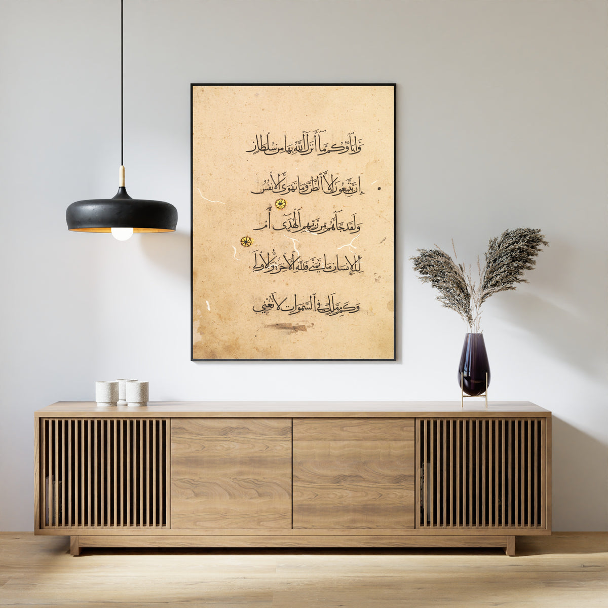 Framed art print of Qur'an Folio: Sura al-Najm (Left Page), above a slatted wood sideboard